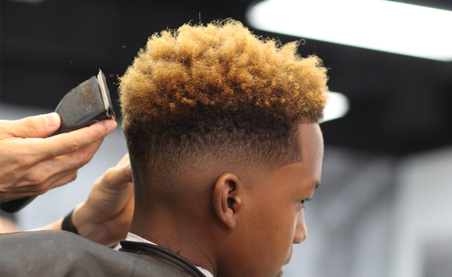A barber shaping a client’s haircut at Fine Line Barbershop.