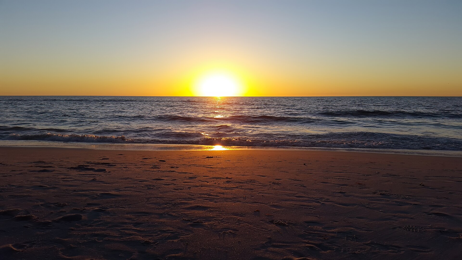 Warm sunset colors over the Gulf shoreline at Naples Beach.